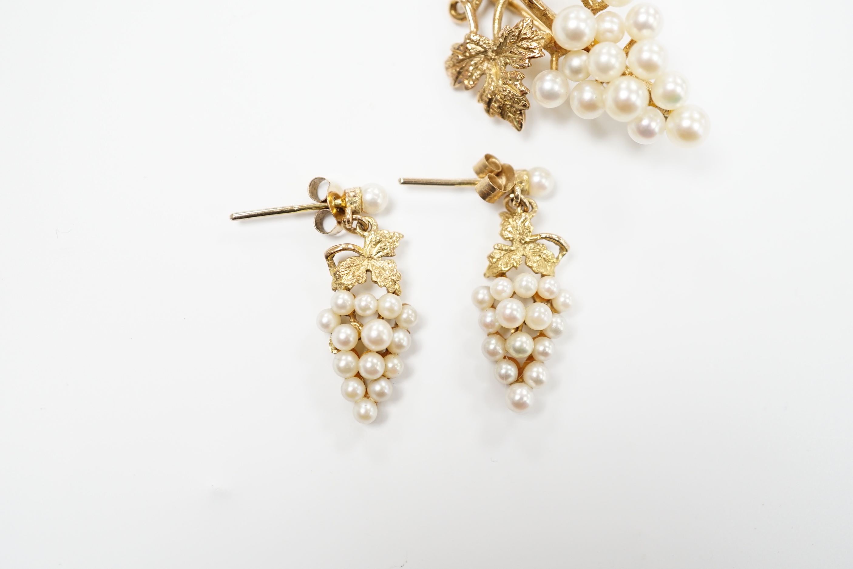 A modern 9ct gold and cultured pearl cluster set suite of jewellery, modelled as a bunch of grapes, comprising a brooch and pair of earrings, gross weight 7.3 grams.